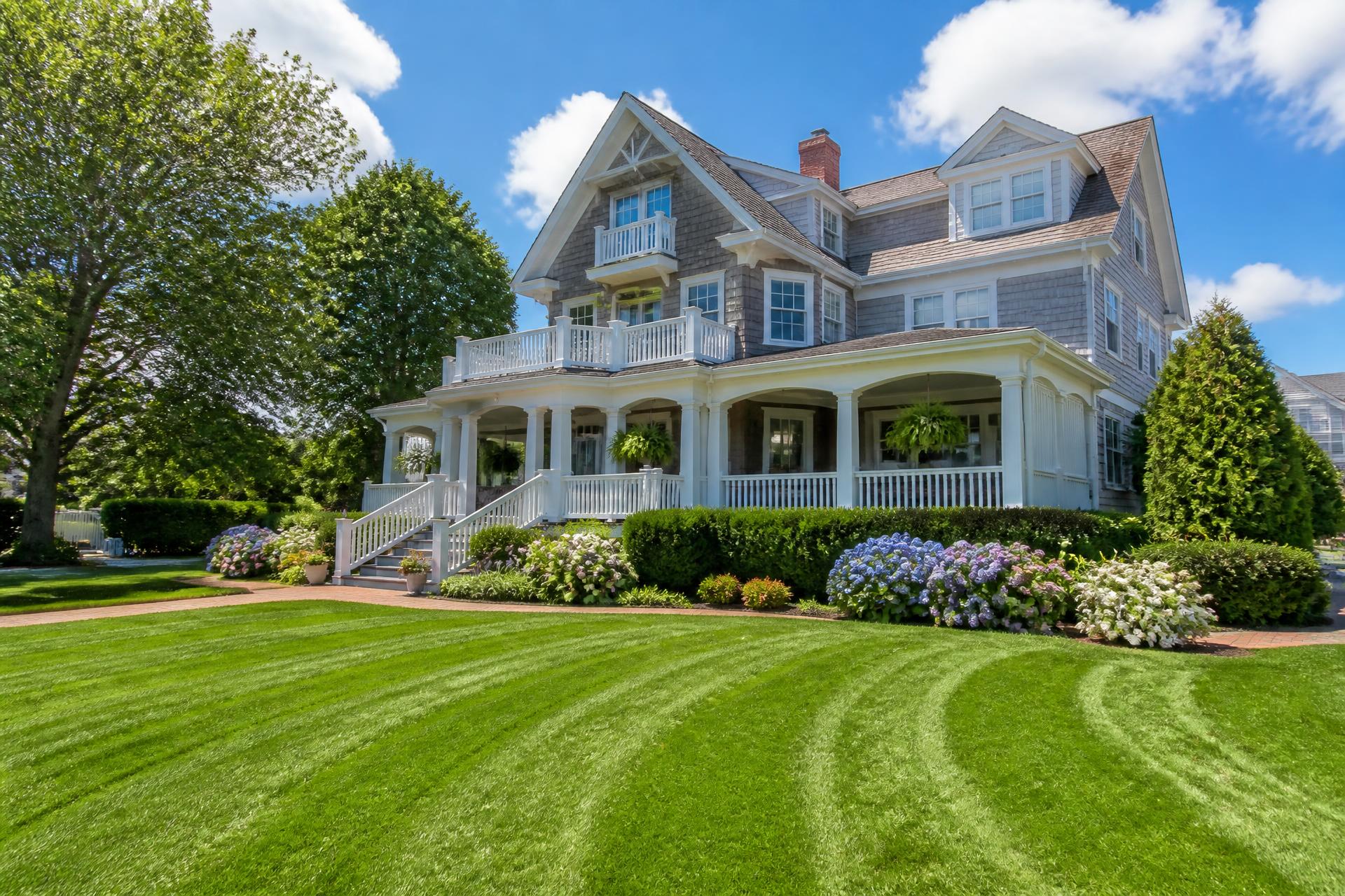 Large sunlit Cape May, New Jersey shore home with a freshly mowed striped green lawn and hydrangea beds